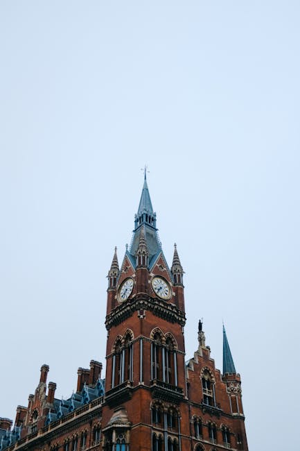 The image displays the exterior of a historic multi-storey red brick building with ornate architectural details, featuring large arched windows bordered with decorative stonework. The building's facad